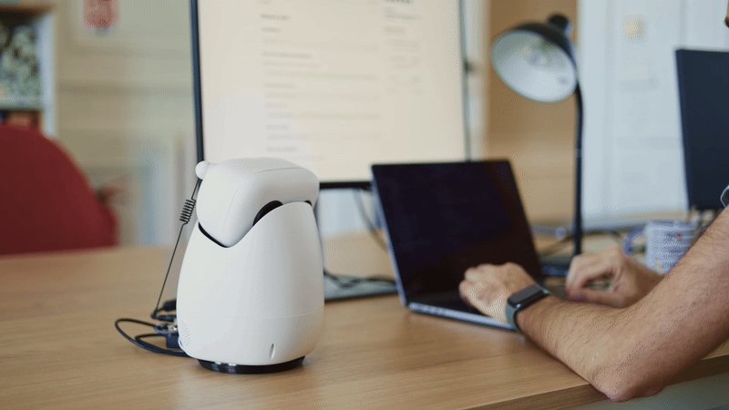 Reachy Mini sitting on a desk next to a laptop